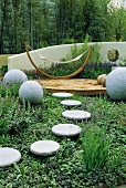 Designte Terrasse und Steinkugeln neben Plattenweg im modernen Garten