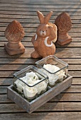 Roses in glasses with a clay rabbit figure on wooden boards