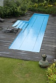 A pool on a wooden terrace in a garden