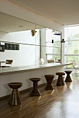 A bar against a wall with a mirror and various wooden designer stools