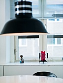 A black pendent lamp above a dining table in front of a window