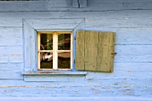 A blue wooden hut with an open window shutter