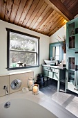Badezimmer mit Badewanne und blauem Waschtisch & Schrank aus Holz