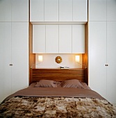 A double bed with built-in cupboards and a built-in bedside table on the headboard
