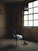 A pair of shoes and a ballet dress on a chair in an old room