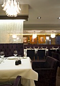 Set table with white tablecloth and a pendant light made of numerous glass elements in a hotel restaurant