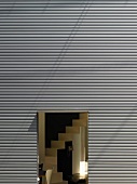 Hausfassade aus Trapezblech mit offener Tür und Blick auf Treppe