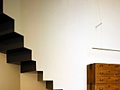 Rustic wood chest of drawers on a wall next to a staircase in contemporary architecture