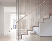 Contemporary staircase with metal grid dividing the staircase from the rest of the room