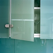 The door of a glass wall unit is ajar in a kitchen