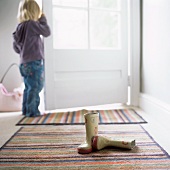 Little girl at the door and a pair of Wellington boots in the hall
