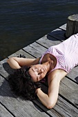 Woman sunning herself on a wooden jetty on the lake
