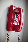 A red touch telephone hanging on a wall