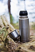 An open Thermos flask on a forest floor