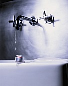 Modern taps and a toothbrush with toothpaste