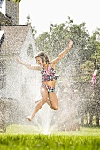 A girl jumping in a sprinkler