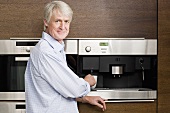A middle aged man waiting for coffee from coffee machine