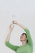 A woman changing a lightbulb