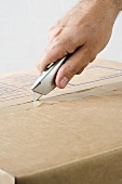 A man opening a box with a carpet knife