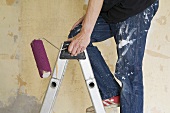 A man on a stepladder with a paint roller