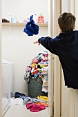 A boy throwing his washing into a laudry basket