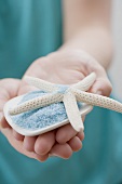 Young woman holding bath salts with starfish