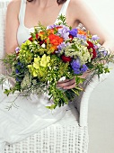 Woman with bouquet of summer flowers sitting in wicker chair
