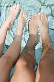 Man and woman dangling their feet in water