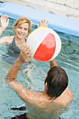 Frau und Mann spielen mit einem Wasserball im Schwimmbecken
