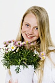 Young girl holding pot of marguerites in her hands