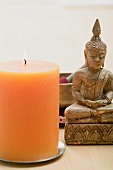 A burning candle with an Asian religious figure