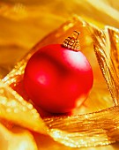Still-life with a red Christmas bauble and gold ribbon