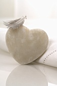White heart-shaped stone and a feather