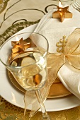 Christmas place-setting with napkin, gold bow, glass of wine