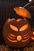 Hand putting lid on pumpkin lantern