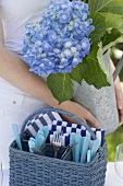 Frau dekoriert Tisch im Garten mit Blumenvase