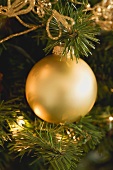 Gold bauble on artificial Christmas tree