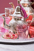 Silver teapot, glasses, roses and windlights on tray