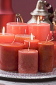Verschiedene rote Kerzen auf Tablett, Teekanne im Hintergrund