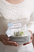 Woman holding pile of plates with Xmas decorations & place cards