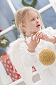 Small girl with angel's wings holding Christmas bauble
