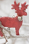 Wooden reindeer on frost-covered branch out of doors