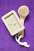 Olive soap and brush on purple terry towel