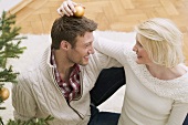 Woman putting Christmas bauble on man's head
