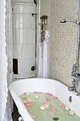 Nostalgische Badewanne mit im Badewasser schwimmenden Rosenblüten