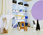 Ironing board with shirt, boxes and storage jars on shelves