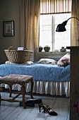 Schlafzimmer in schwedischem Haus mit hellem Holzdielenboden und einem Einzelbett mit pastellblauem Überwurf mit weisser Rüsche