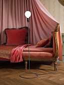 Antikes, samtbezogenes Sofa mit rosa Baldachin und eigenwilliger Stehlampe
