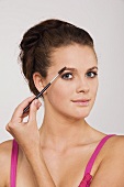 Young woman using an eyebrow pencil, portrait