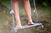 Child standing on swing barefoot